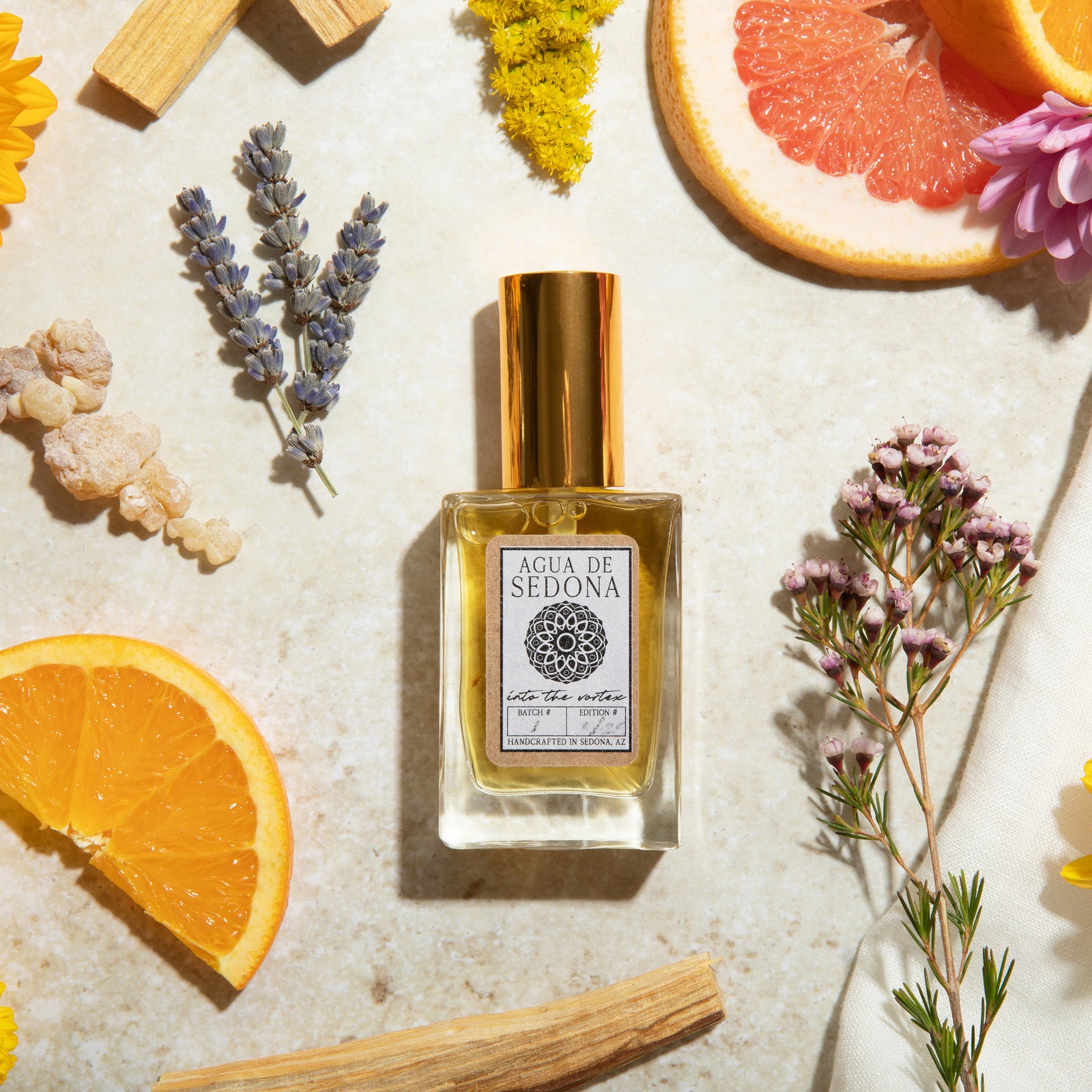 Agua de Sedona Into the Vortex perfume bottle with citrus and florals on the background